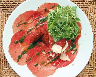 Salade de roquette sur Carpaccio de Bœuf au pesto, huile d'olive aux piments et copeaux de parmesan - 