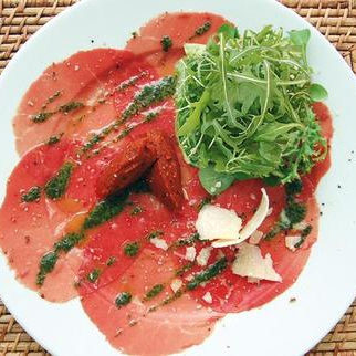 Salade de roquette sur Carpaccio de Bœuf au pesto, huile d'olive aux piments et copeaux de parmesan - 